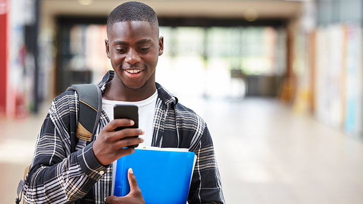 Male college student smiling at smartphone
